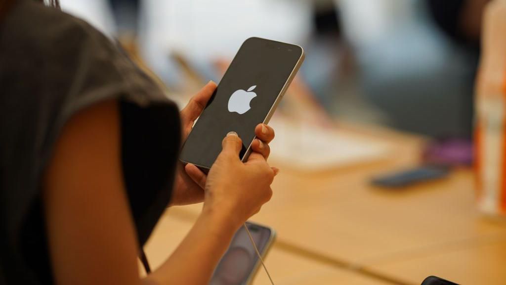 A woman holds an iPhone displaying an Apple logo while in an Apple store