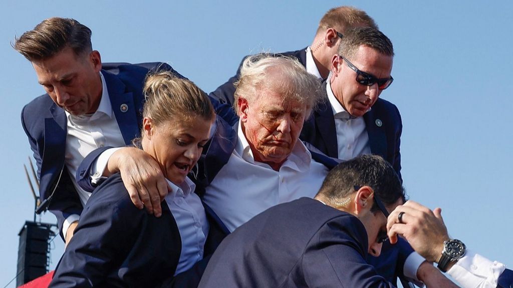 Trump is surrounded by Secret Service agents as he's escorted off stage moments after the shooting