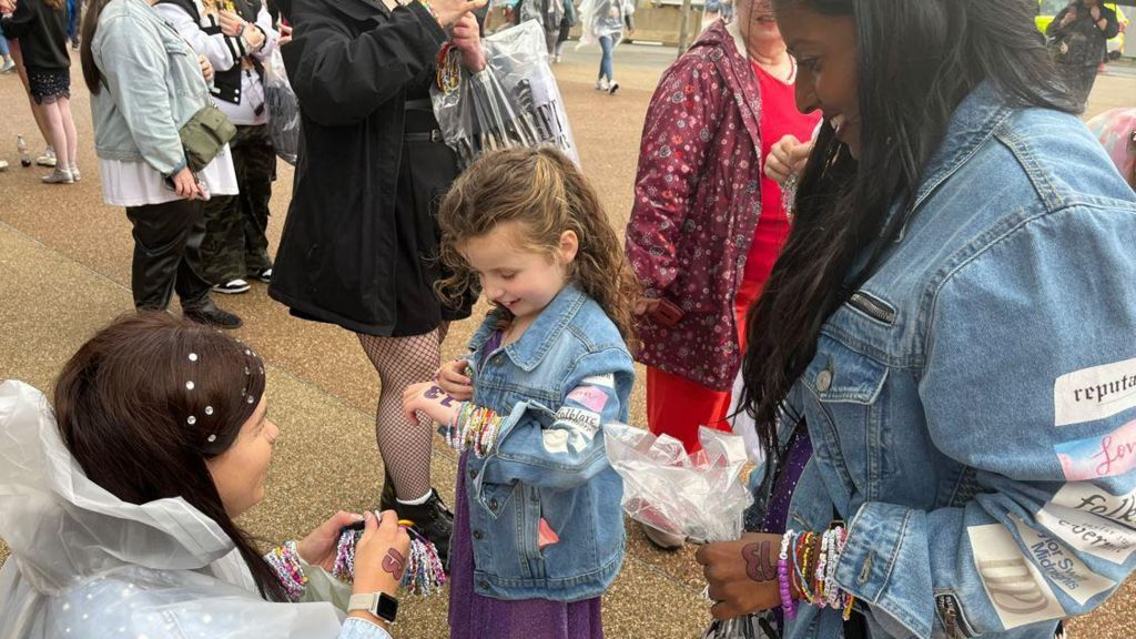 Young Florence admires a friendship bracelet given to her by another Taylor Swift fan, while Brinda Selvamanoharan  looks on 