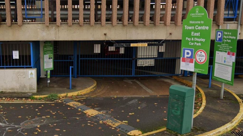 Entrance to an underground car park, with the road curving to the left to the entry. A signboard welcoming drivers with the borough council's green and white logo and branding is also visible.