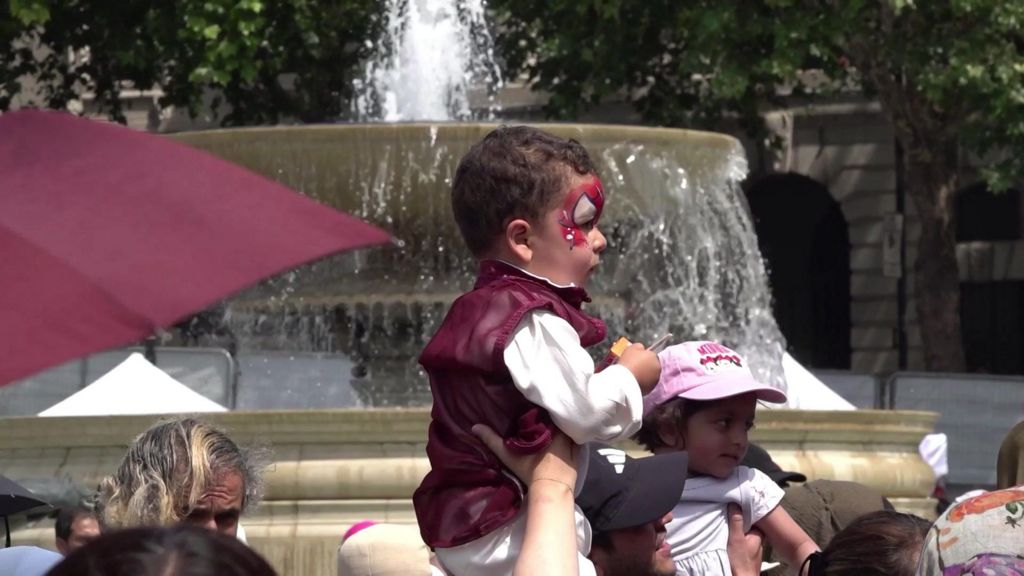 A young child carried on a man's shoulders as they pass a fountain