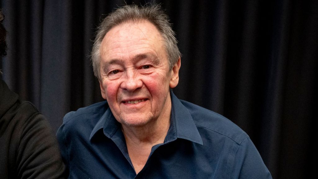 A head and shoulders shot of Paul Whitehouse smiling and looking at the camera while wearing a blue shirt against a black background, photographed on 5 December 2024