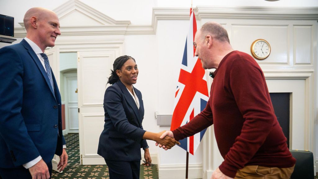 Mark Hehir shaking hands with Kemi Badenoch during a meeting at Westminster, with Kieran Mullan standing nearby