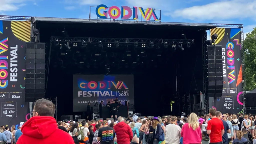 People in front of the main stage at the Godiva Festival in 2024. The stage has a lot of branding saying 