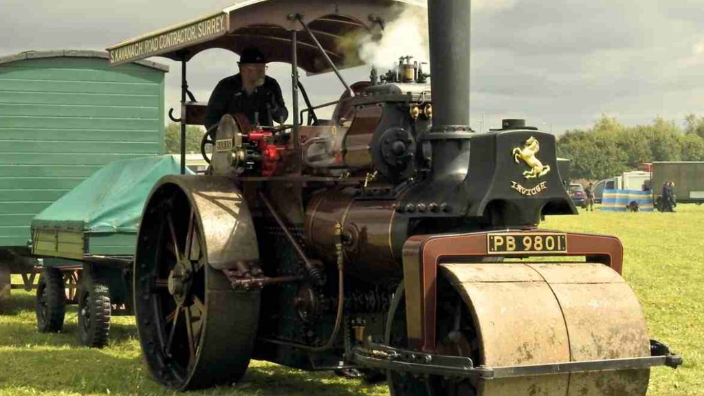 A man on a vintage-style brown and black tractor on grass