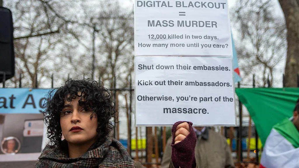 a woman with curly hair holds up a sign that reads 
