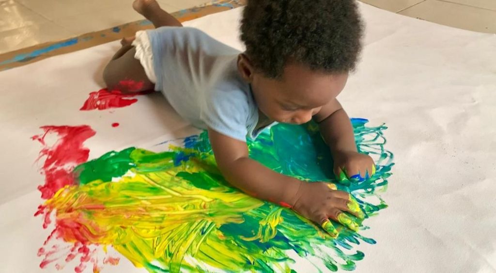 A baby painting on stretched out canvas 