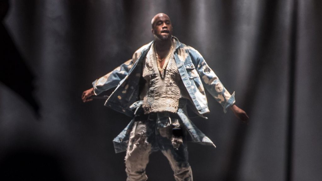 Kanye West with his arms outstretched on the stage at Glastonbury in 2015
