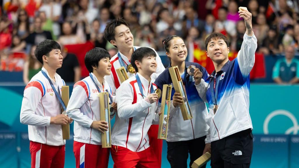 A South Korean athlete takes a selfie with his teammate and duos from North Korea and China