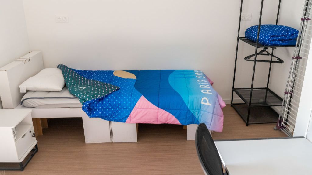 A bedroom in the Paris 2024 athletes' village, with bed, bedside table, hanger and table.