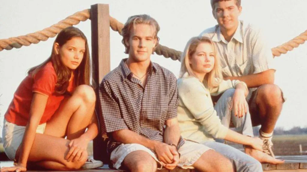 Katie Holmes, James Van Der Beek, Michelle Williams, and Joshua Jackson sit on a board walk and pose for a photo