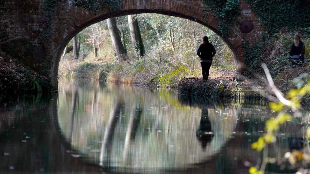 People make their way along the Basingstoke Canal near to Dogmersfield in Hampshire
