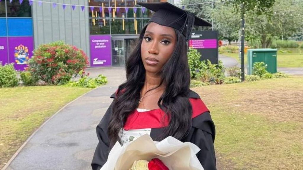 Theresa is wearing a cap and gown at her Aston University graduation.