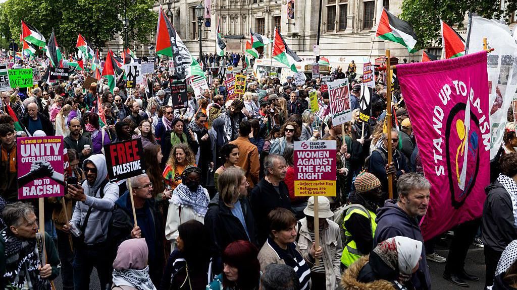 At least 100 people are seen in a picture from a portion of the Nakba Anniversary march in London - about a dozen Palestinian flags can be seen in the background, as well as placards in the foreground that say things like 'Free Palestine' and 'Unity over division'