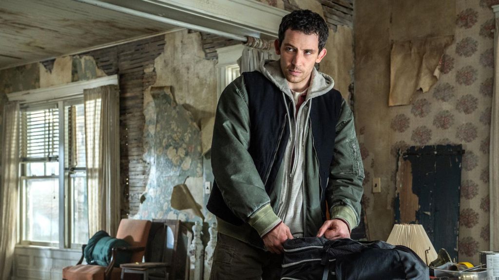 Josh O'Connor standing in a grand but fading room, opening a bag