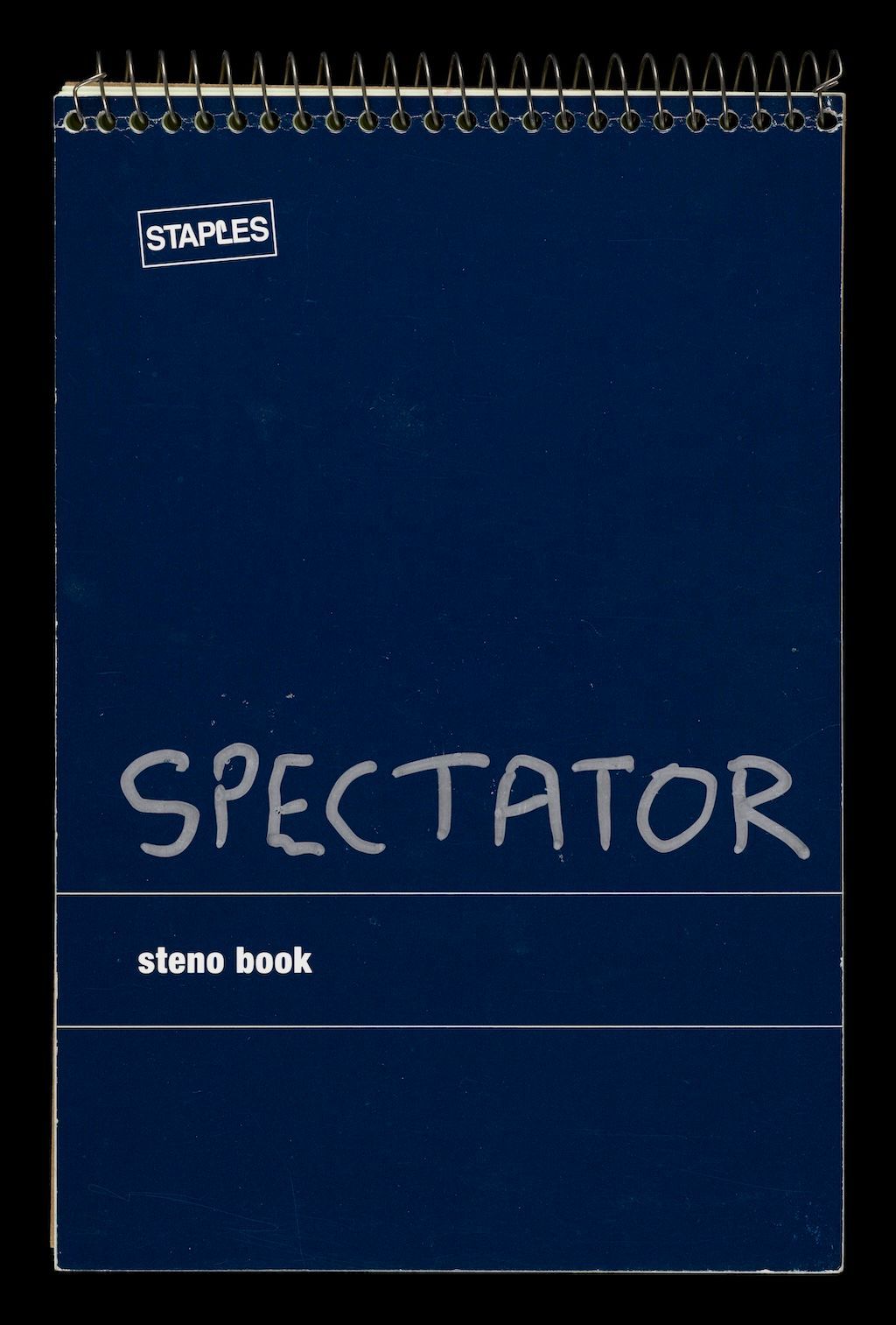 A blue spiral-bound notebook, with the word Spectator written across the front in silver pen