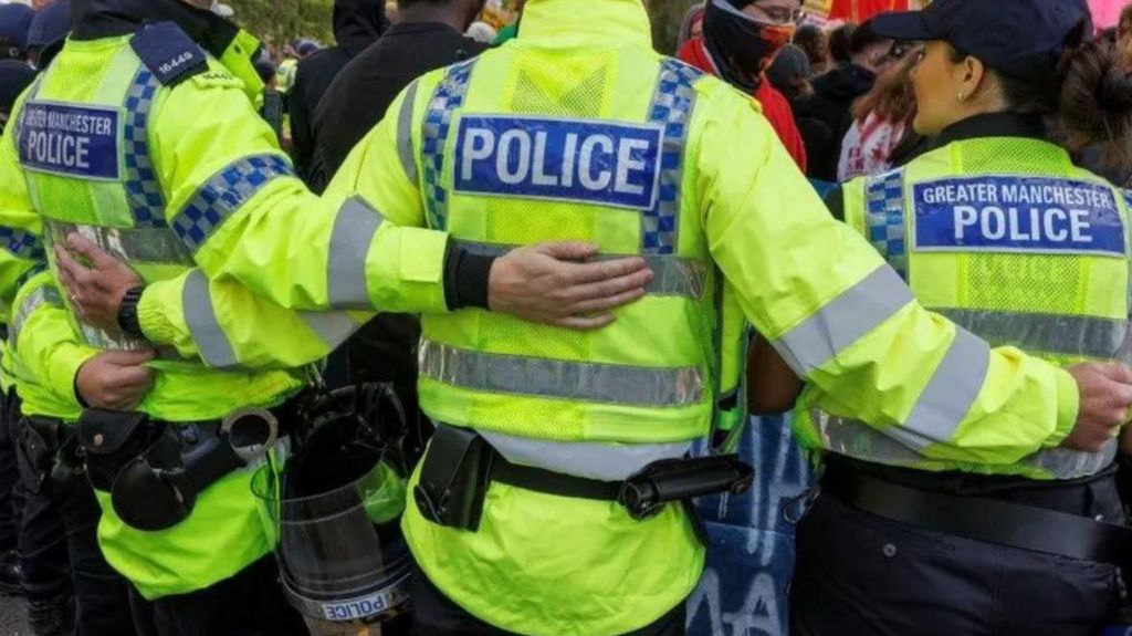 Greater Manchester Police officers holding back protesters 