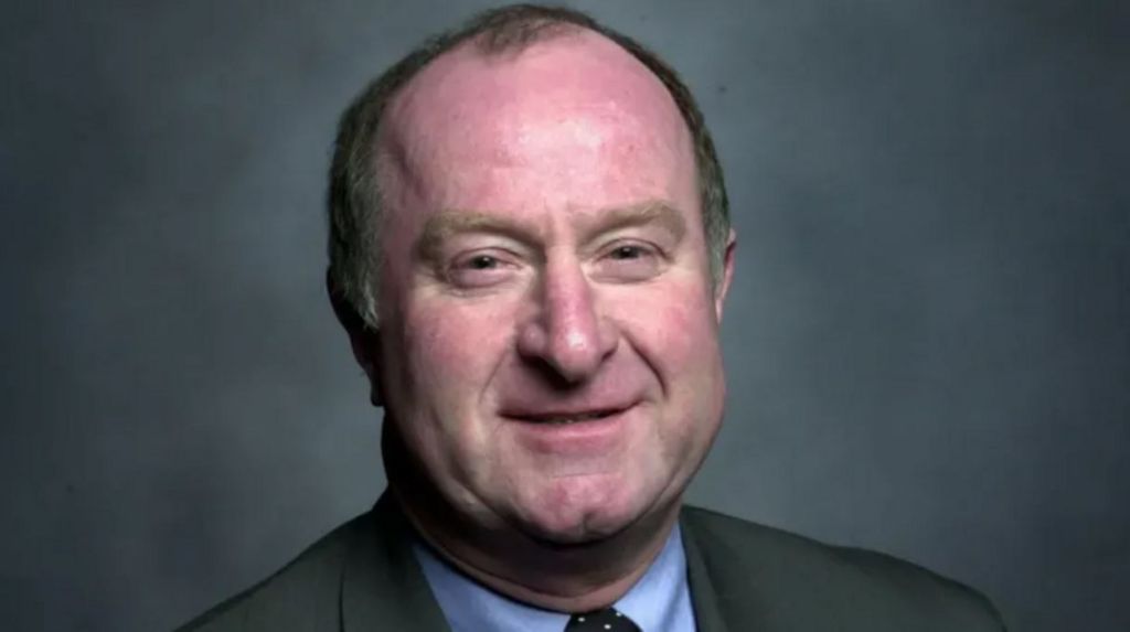 Councillor Mike Bird, wearing a grey suit jacket, blue shirt and spotty tie