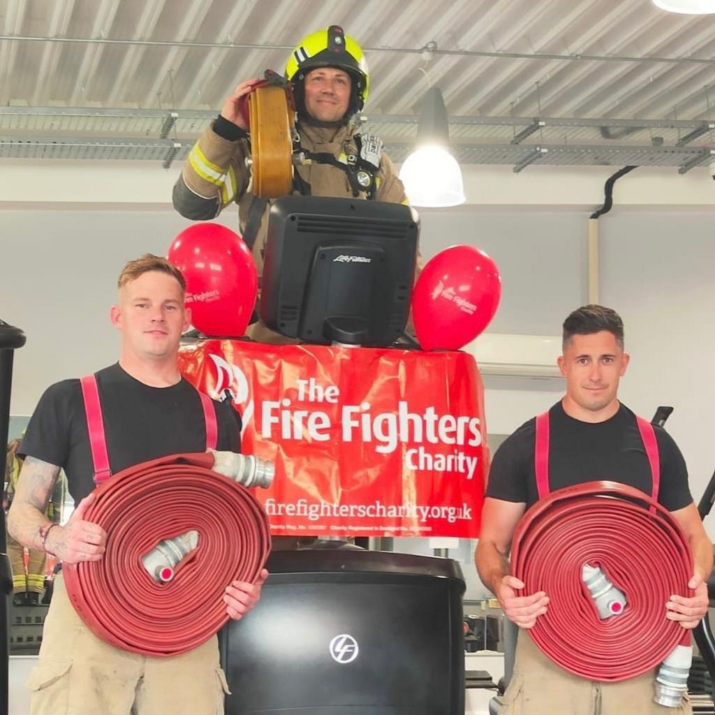 (L-R) Tom Martin, James Crook and Danny Toop pose with fire hoses. James is in full uniform and helmet