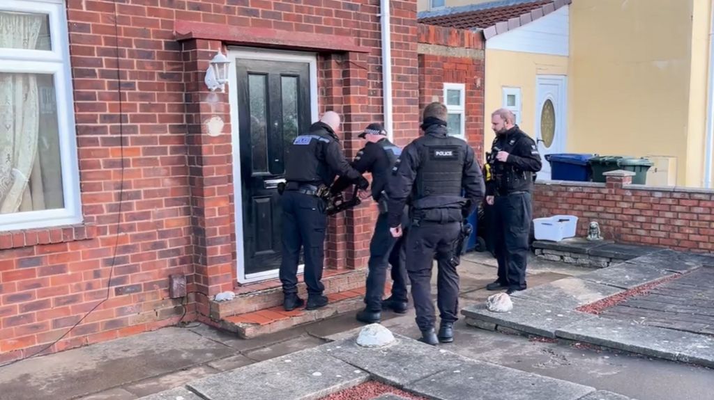 Police atempting to break down a door during a drugs raid as part of Operation Artemis