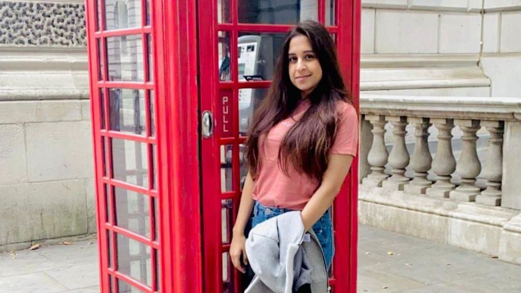 Raheema standing in front of a telephone box 