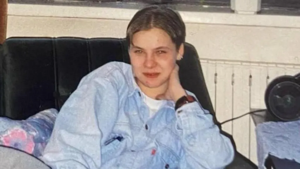 A woman sat on a sofa in a denim-like jacket. 