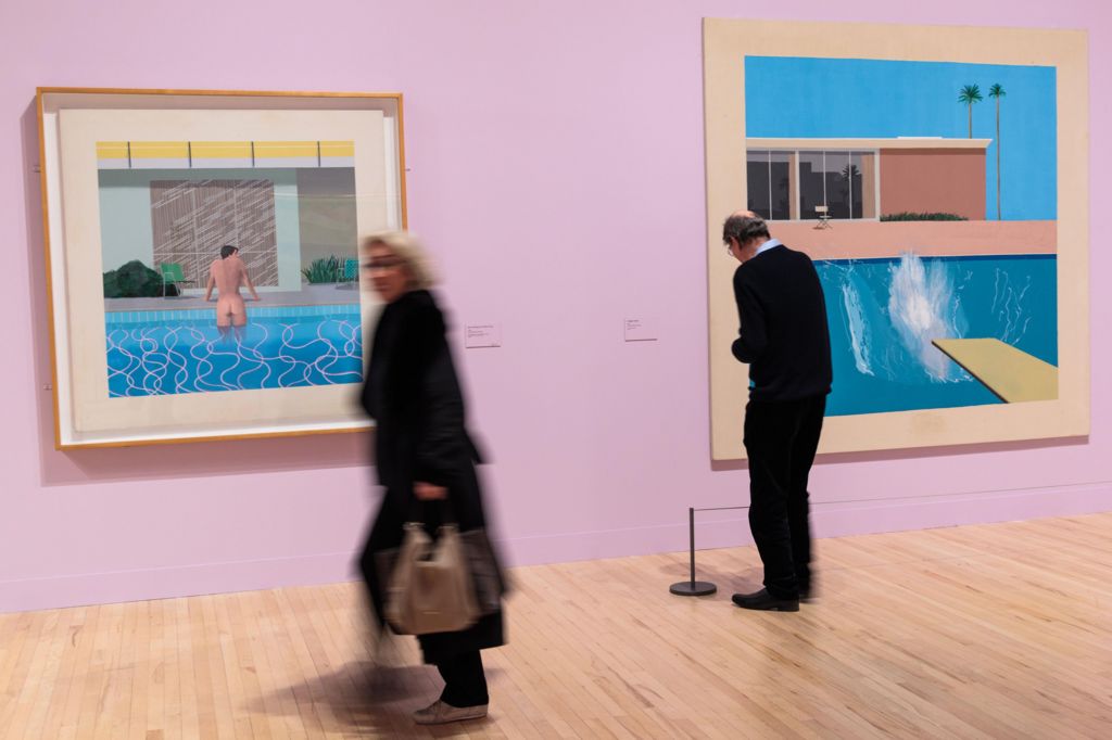 Visitors to 2017 Tate Britain exhibition look at 'Peter Getting Out of Nick's Pool', 1966 (L) and 'A Bigger Splash', 1976 (R)