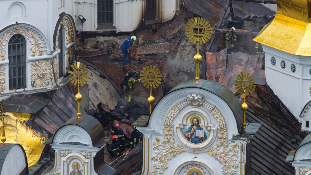 Ukrainian firefighters work at the roof of the damaged Dormition Cathedral