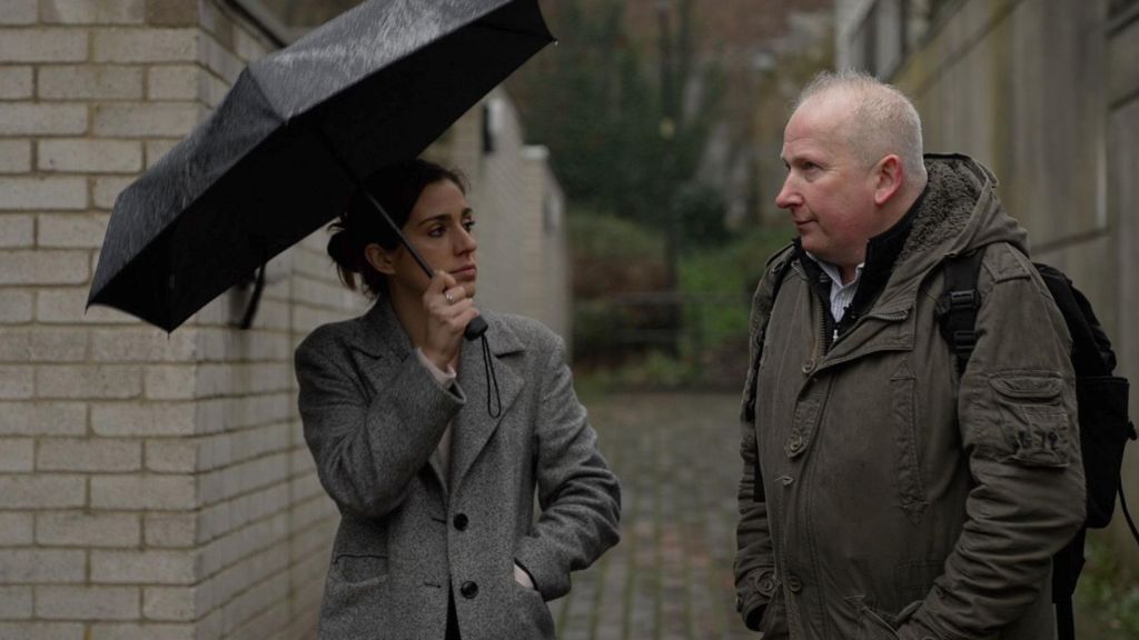 Meghan Owen holds an umbrella and is talking to Pete Elliott in the estate