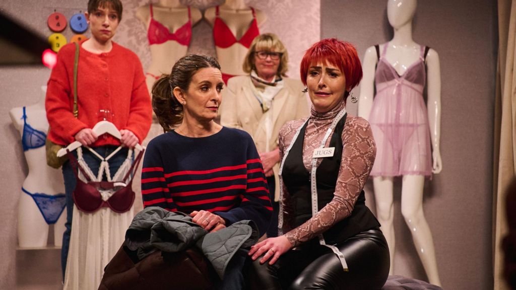Tina Fey and Emma Sidi, wearing a cropped red wig, in the changing rooms of a women's underwear shop