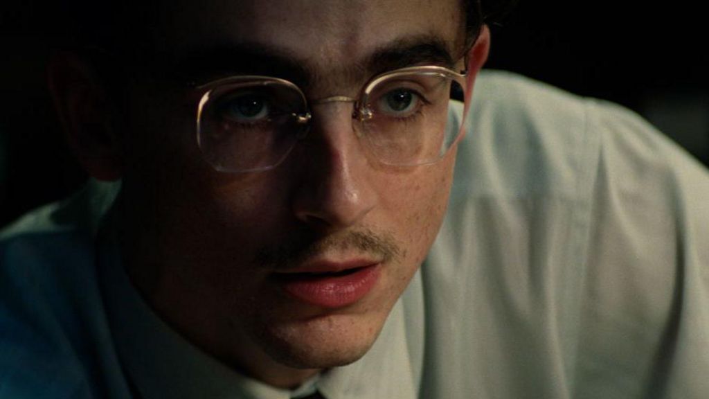 A close-up of Timothee Chalamet with glasses, a moustache and shirt in Marty Supreme