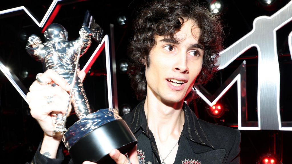 Sombr holding a silver astronaut, the MTV VMA Moon Man trophy, at the 2025 MTV Video Music Awards