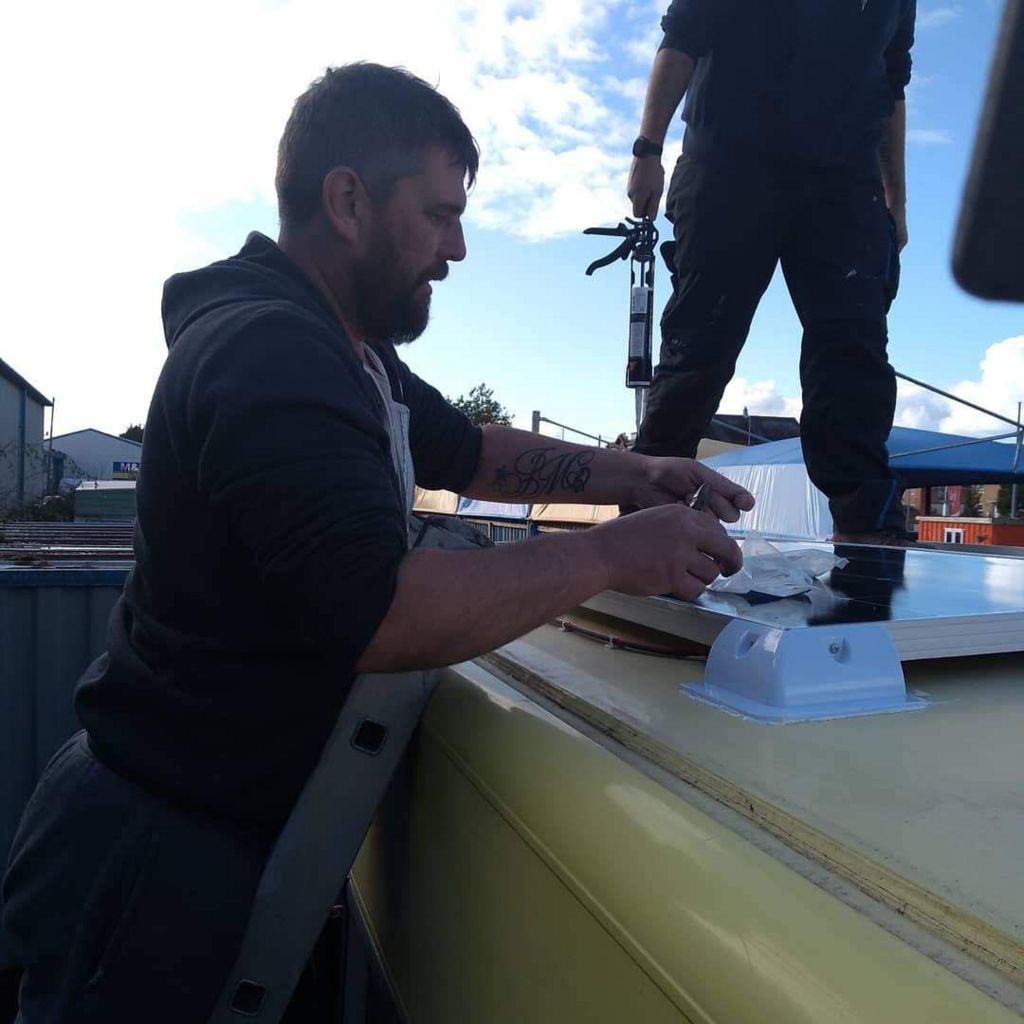 A man fixes something to the roof of a bus.