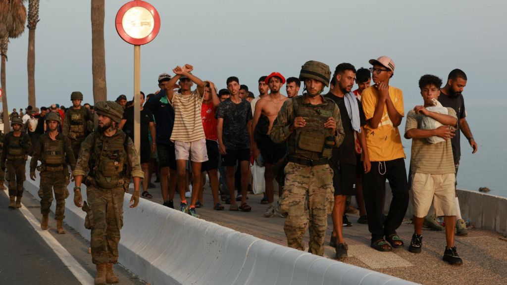 Members of the military escort migrants in Ceuta, Spain, following recent mass crossings of migrants on foot and by sea from Morocco into Spanish territory.