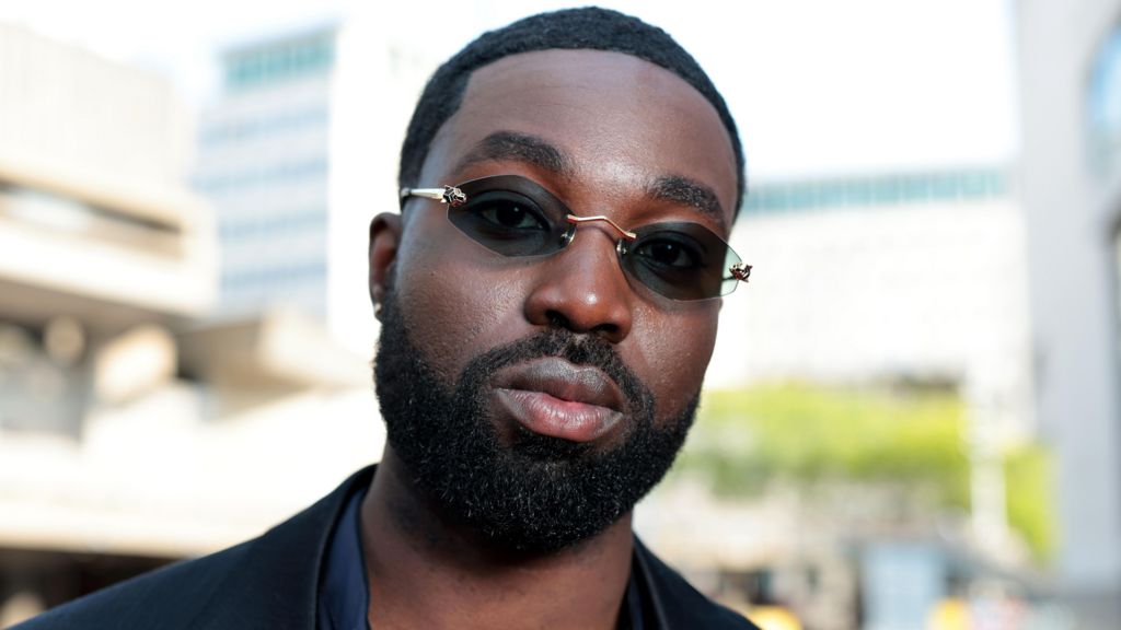 Paapa Essiedu wearing a black jacket and sunglasses