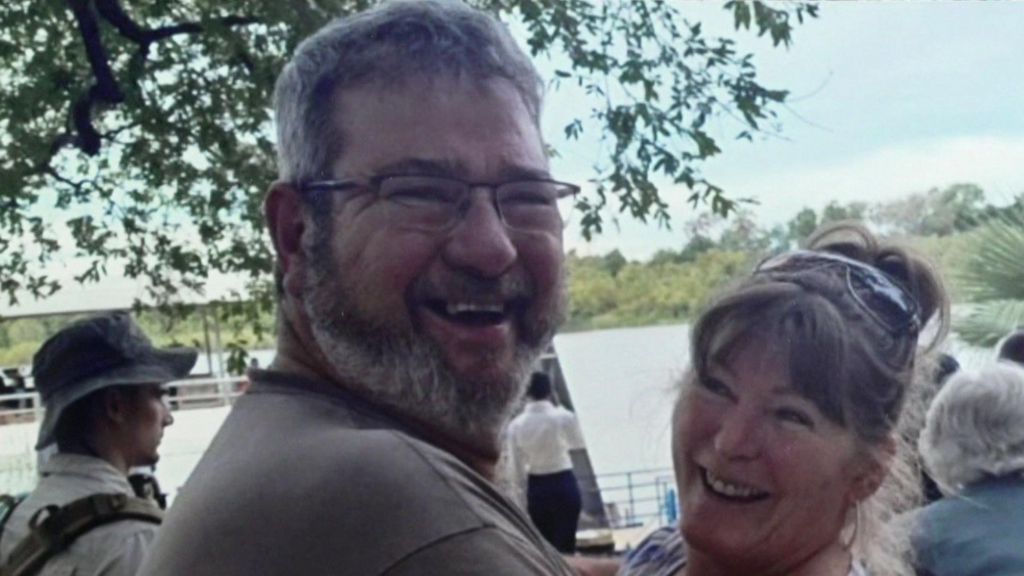 Jono and Sarah Armstrong with their arms around one another both looking at the camera and smiling