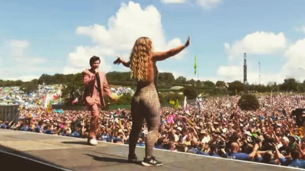 Lauren Filer in a catsuit standing onstage with Rick Astley in front of thousands of people