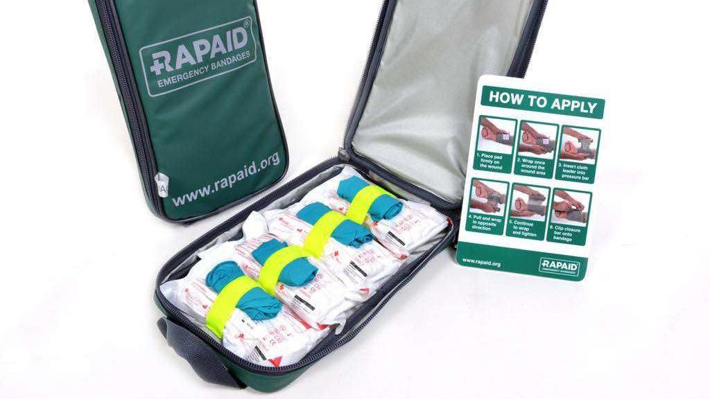 The contents of a bleed kit which include a tourniquet, a chest seal, gauze, protective gloves and a sheet of instructions.