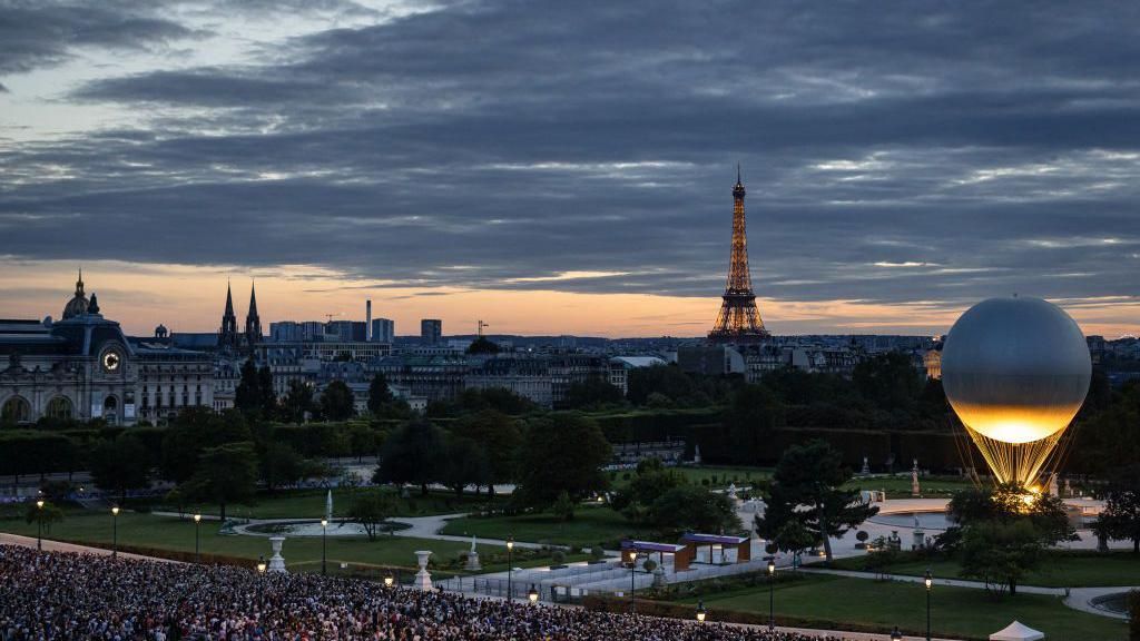 Image from the opening of the Paris Olympics which shows the large cauldron lit and the Eiffel tower in the background.