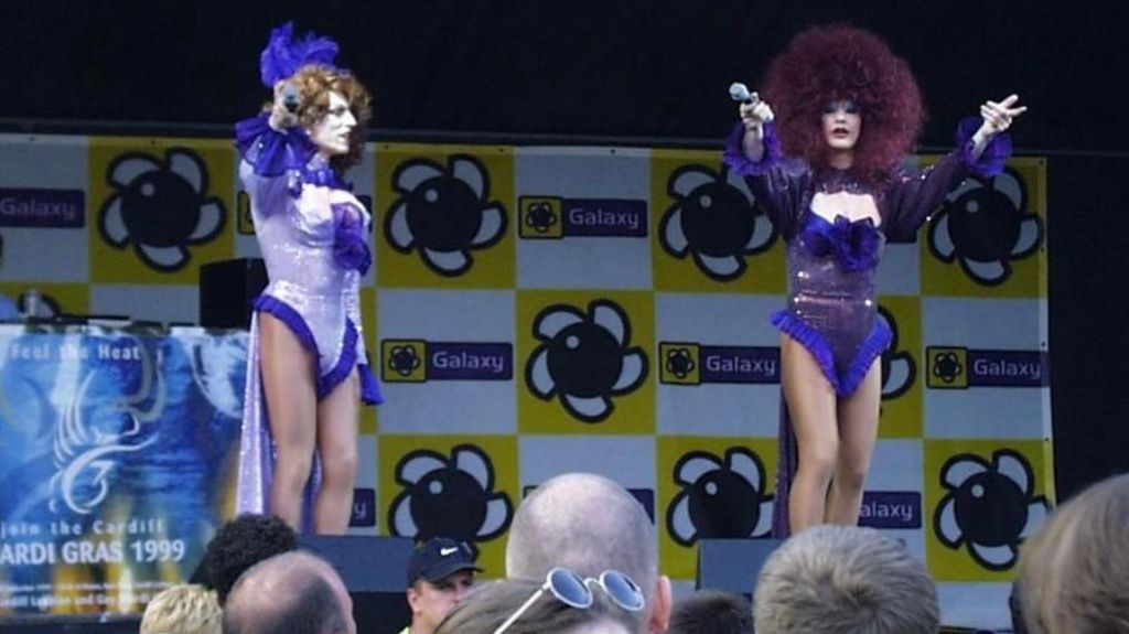 Two drag queens in purple on a stage