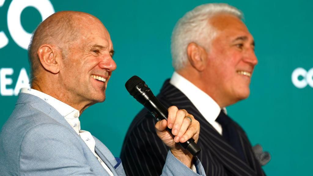 Adrian Newey holds a microphone portion    sat adjacent  to Lawrence Stroll 