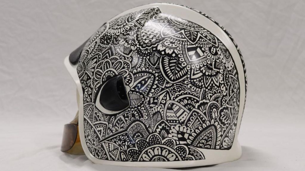 A helmet painted in a busy overlapping black and white design