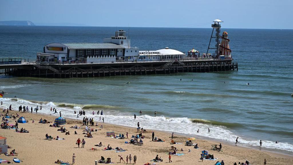 Library image of people on the beach and in the sea east of Bournemouth Pier