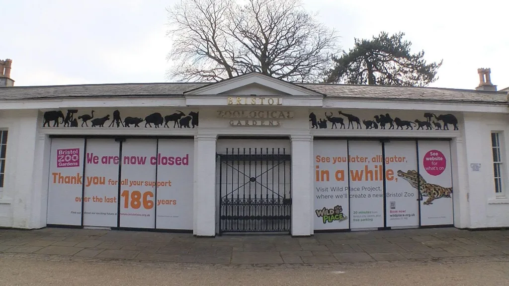 The exterior of the old Bristol Zoo Gardens - a traditional white one-storey building with pitched roof, likely Victorian, with metal gates.