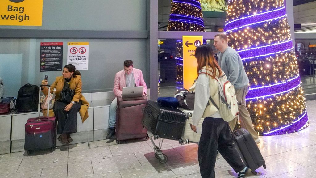 Travellers with suitcases walked past a tall decorated Christmas tree at Heathrow Airport on 30 November 2025