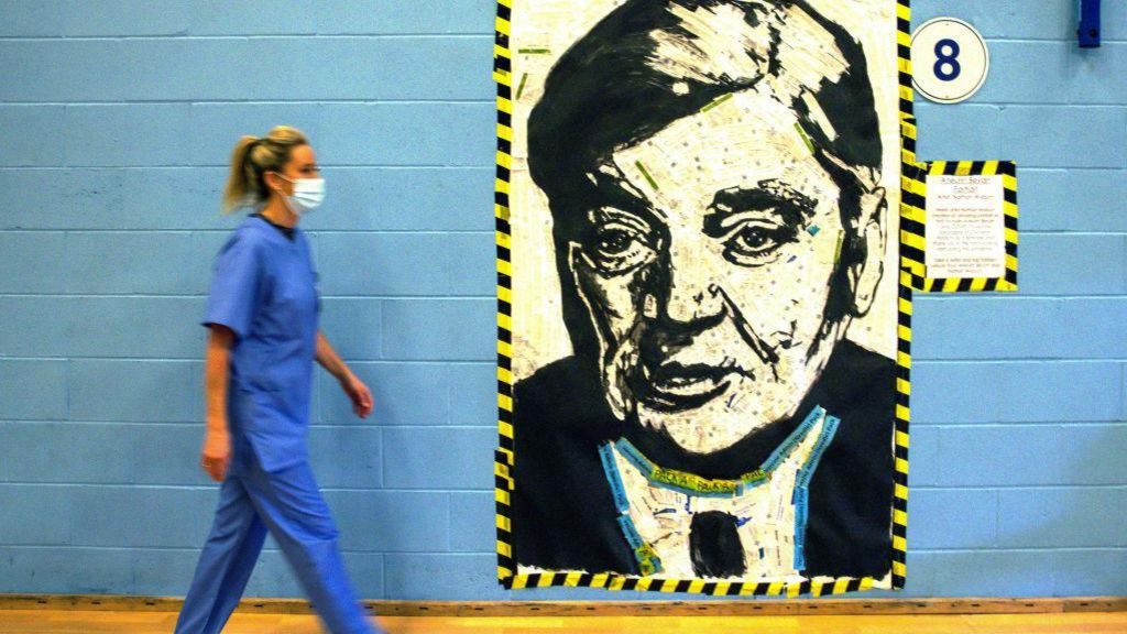 A Nurse walks past a portrait of Aneurin Bevan the architect of the NHS on 5 October 2021 in Cwmbran