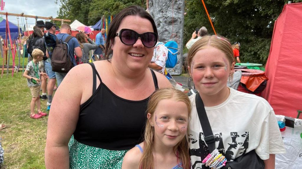 A mum in a black strappy top with her two girls in a play area.