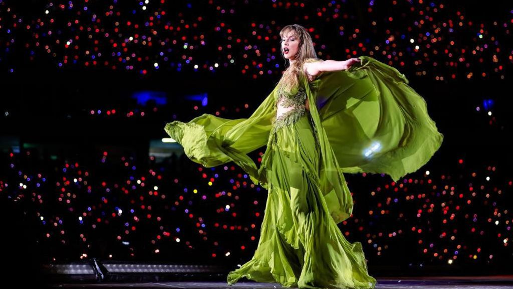 Taylor Swift in a flowing green dress during her Eras Tour on stage