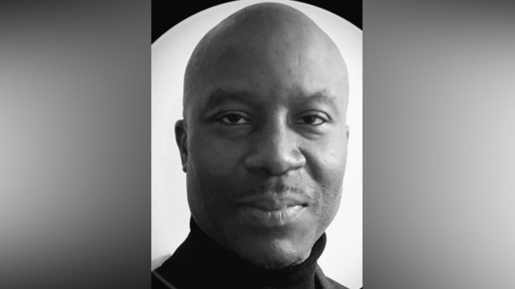 A black and white photo of Simon Whyte in a black roll neck jumper.