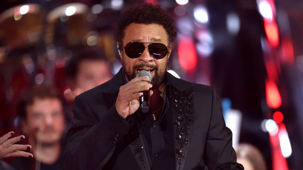 Shaggy performing in 2021, wearing a black, bejewelled suit jacket and sunglasses.